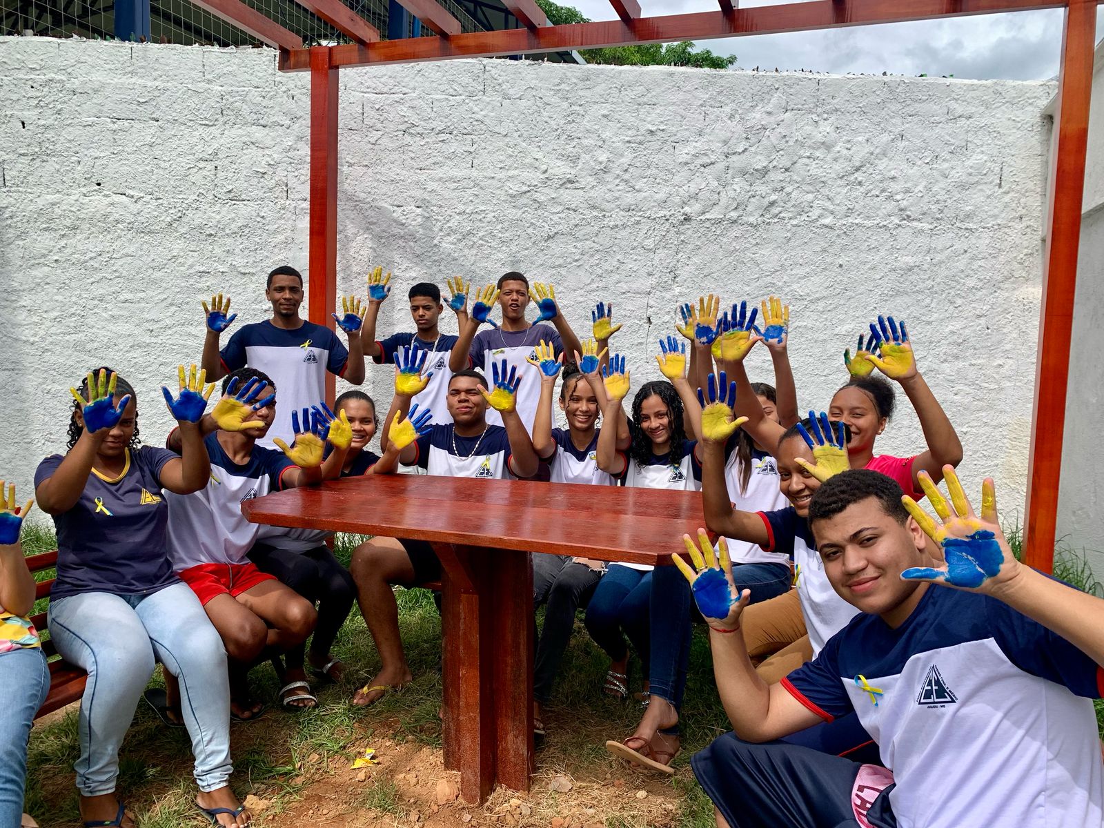 Foto de um grupo de estudantes mostrando as palmas das mãos, que estão pintadas de azul e amarelo